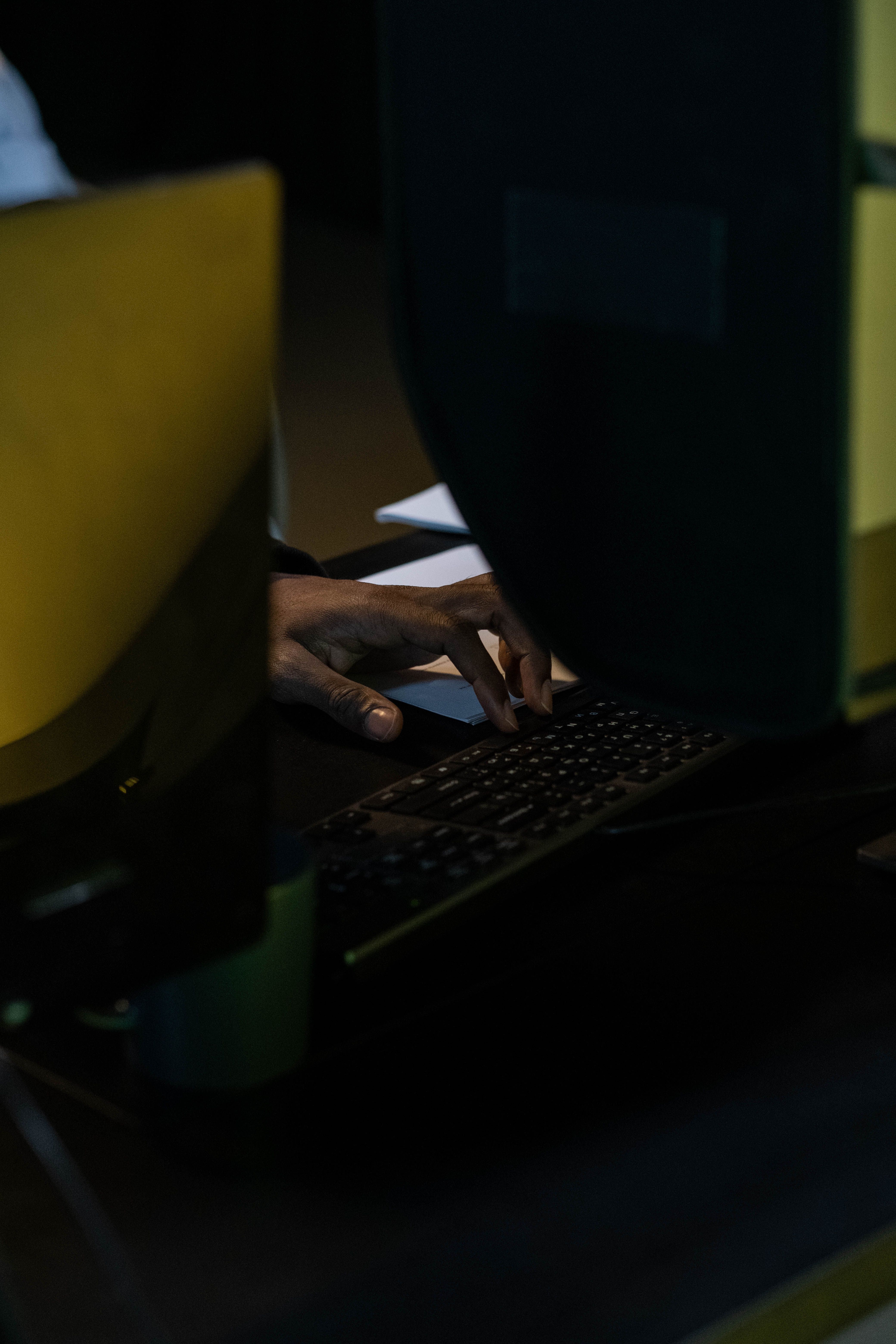 Рука друкує на клавіатурі в темному приміщенні